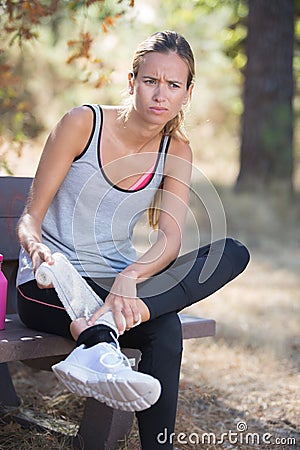 Fitness woman suffering painful ankle sprain injury after running Stock Photo