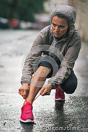 Fitness woman tying shoelaces outdoors in city Stock Photo