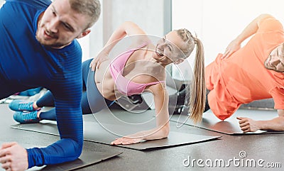 Fitness woman and men in the health club doing a side plank Stock Photo