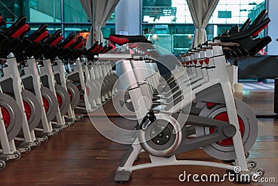 Fitness Workout in Gym: Group of Modern Spinning Bikes in Line Stock Photo