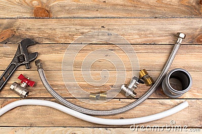 Fittings, pipe, valves, plastic pipe for water, water hose, adjustable wrench on the wooden background. Top view. Copy space for Stock Photo