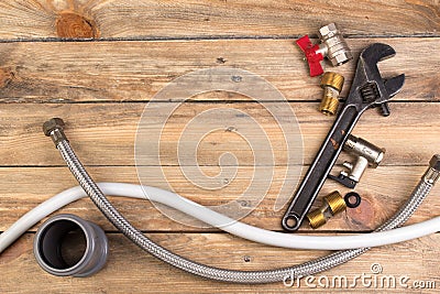 Fittings, pipe, valves, plastic pipe for water, water hose, adjustable wrench on the wooden background. Top view. Copy Stock Photo