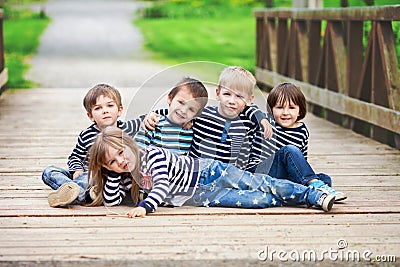 Five adorable kids, dressed in striped shirts, hugging and smiling Stock Photo