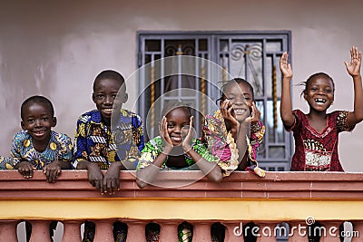 Five African Children Greeting Bypassers From A Colonial House Balcony Stock Photo