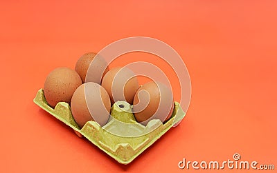 Five brown eggs instead of six in an open egg carton on orange background. Shrinkflation concept. Stock Photo