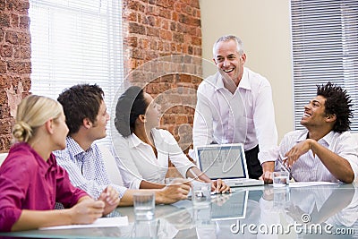 Five businesspeople in boardroom with laptop Stock Photo