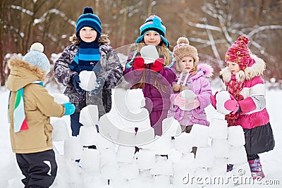 Five children build wall from snow bricks Stock Photo