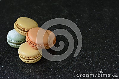 Five colorful macaroons in a pile on a black background. Five tasty cookies Stock Photo