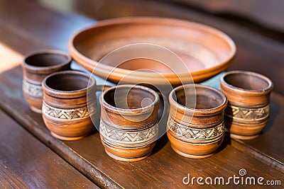 Five cups and a bowl of red clay with Ukrainian ornament on the wooden table closeup Stock Photo
