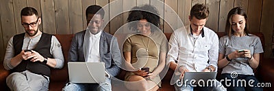 Five diverse businesspeople girls guys sitting on couch using gadgets Stock Photo