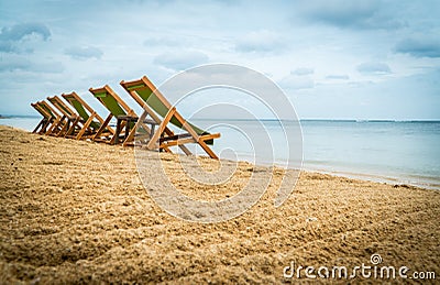 Five empty green beach chairs facing the ocean Stock Photo