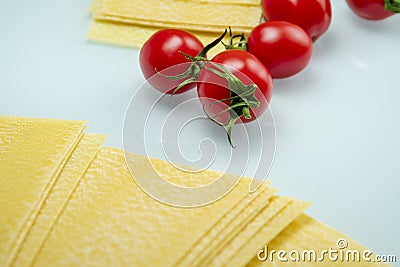 Tomatoes between lasagna on white reflexive glass Stock Photo