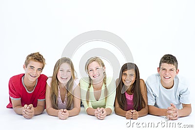 Five friends lying down in a row smiling Stock Photo