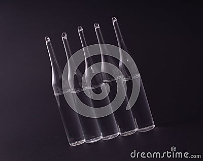 Five ampoules in a row on a black background Stock Photo