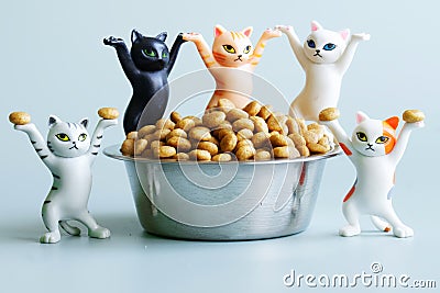 Five funny toy kittens next to a bowl filled with dry cat food. The concept of food for pets Stock Photo