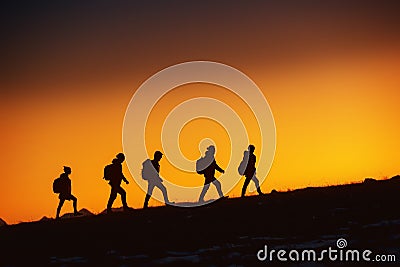 Five hikers going uphill at sunset Stock Photo