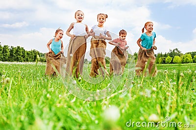 Five kids having fun jumping in sacks Stock Photo