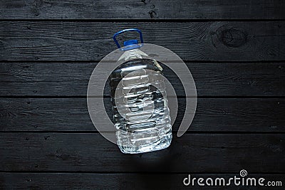 A five-liter plastic water bottle lies on a black wooden board Stock Photo