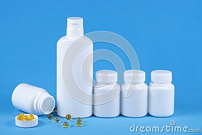 Five pills medicine bottles on blue background with copy space for text. Toppled over box, spilled orange pills Stock Photo