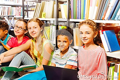 Five smiling children sitting in a row on floor Stock Photo