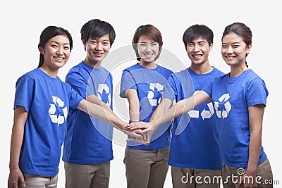 Five smiling and happy young people in a row wearing recycling symbol t-shirts with hands together, studio shot Stock Photo