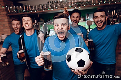 Five soccer fans drinking beer celebrating and cheering at sports bar. Stock Photo