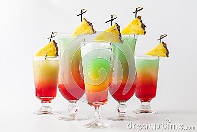 Five tall colourful mocktails garnished with pineapple wedges against a light background. Stock Photo