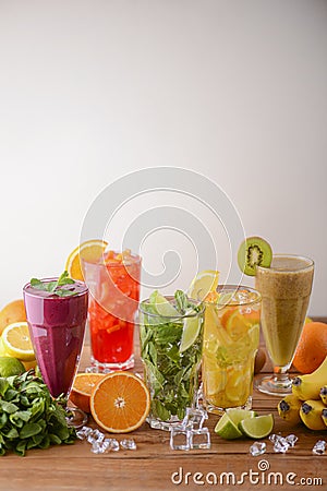 Five tropical mixed drinks, orange, lemon, kiwi fruit, mint, lime and raspberries cocktails served on wooden table. Stock Photo