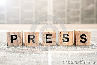 Five wooden cube blocks with the text press on a newspaper background Stock Photo