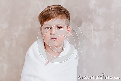 Five year old Caucasoid cute boy wrapped in white Terry towel looking at camera Stock Photo