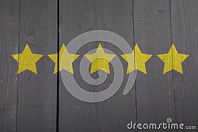 Five yellow ranking stars on wooden background Stock Photo