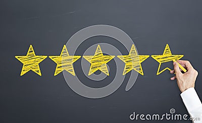 Five yellow stars drawn with chalk on black chalkboard. customer voting concept Stock Photo