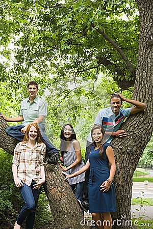 Five young friends around a tree Stock Photo