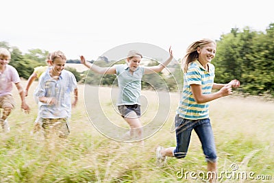 Five young friends running in a field smiling Stock Photo