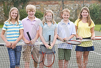 Five young friends on tennis court smiling Stock Photo