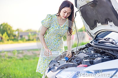 Fixing Her Broken Down Car, a young woman pours a water for washing glasses into her car Stock Photo