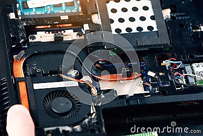 Fixing laptop. Repairman holds cooling fan and repairs from overheating. Disassembling computer, replacement, clean dust Stock Photo