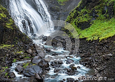 Fjordland, West Iceland - Waterfall tumbles into lush green valley Stock Photo