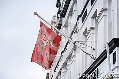 The flag of the Isle of Man or flag of Mann is a triskelion, composed of three armoured legs with golden spurs, upon a red Stock Photo