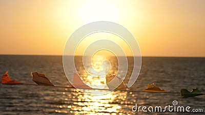 Flags develop in the wind against the background of the sea on the beach during sunset. Sea Waves Landscape Stock Photo