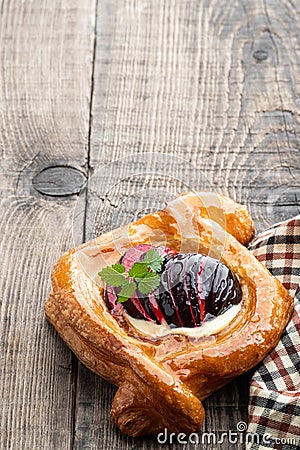 Flaky pastry with plum on wooden table Stock Photo