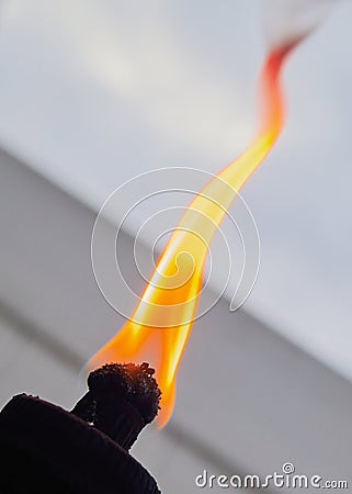 orange flame and burning wick on an oil torch against an overcast sky in the backyard Stock Photo