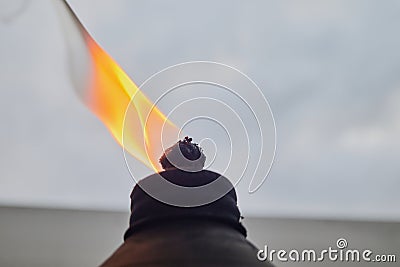 orange flame and burning wick on an oil torch against an overcast sky in the backyard Stock Photo