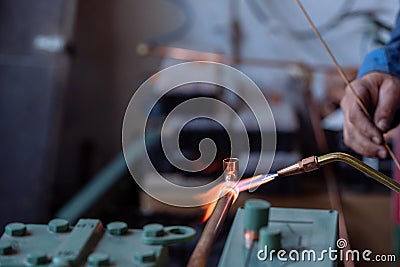 Flame of a copper welding machine heats a copper pipe in a workshop Stock Photo