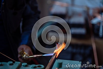 Flame of a copper welding machine heats a copper pipe in a workshop Stock Photo