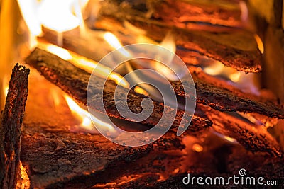 Flame incinerates firewood and transforms it ashes, close up, shallow depth of field. Blaze in a large stove. Nature Stock Photo