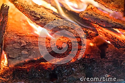 Flame incinerates firewood and transforms it ashes, close up, shallow depth of field. Blaze in a large stove. Nature Stock Photo