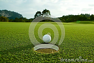 The flare lights photo of white golf ball near hole on fairway w Stock Photo