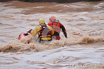 flash flood rescue, with person being pulled from rushing waters and into safety Stock Photo