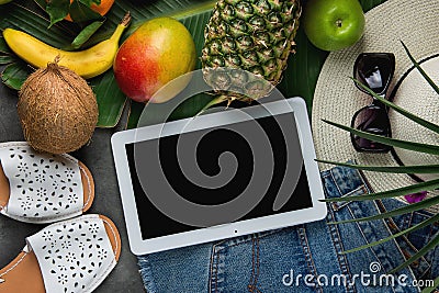 Flat Lay Composition with Tropical Fruits Pineapple Mango Bananas Coconut on Large Palm Leaf. Women Jeans Shorts Slippers Hat Stock Photo